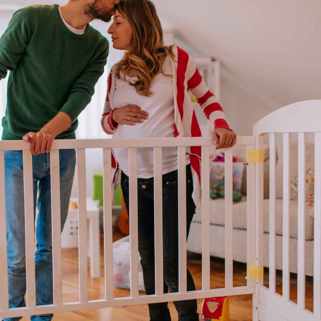 Expecting parents standing next to crib